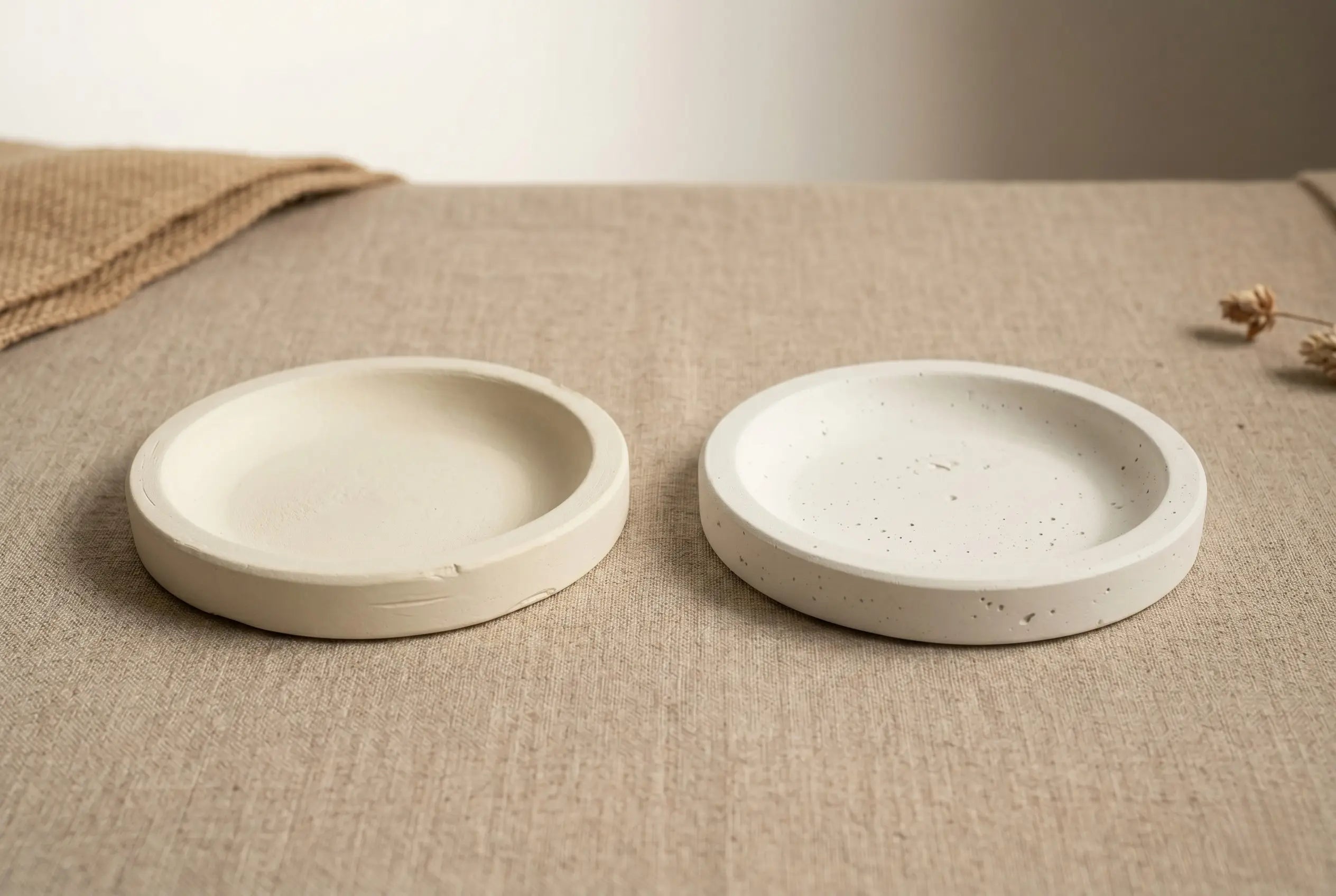 Two cast coasters side-by-side, one made with Artriso CALSO ONE and one with Jesmonite AC100, on a linen surface