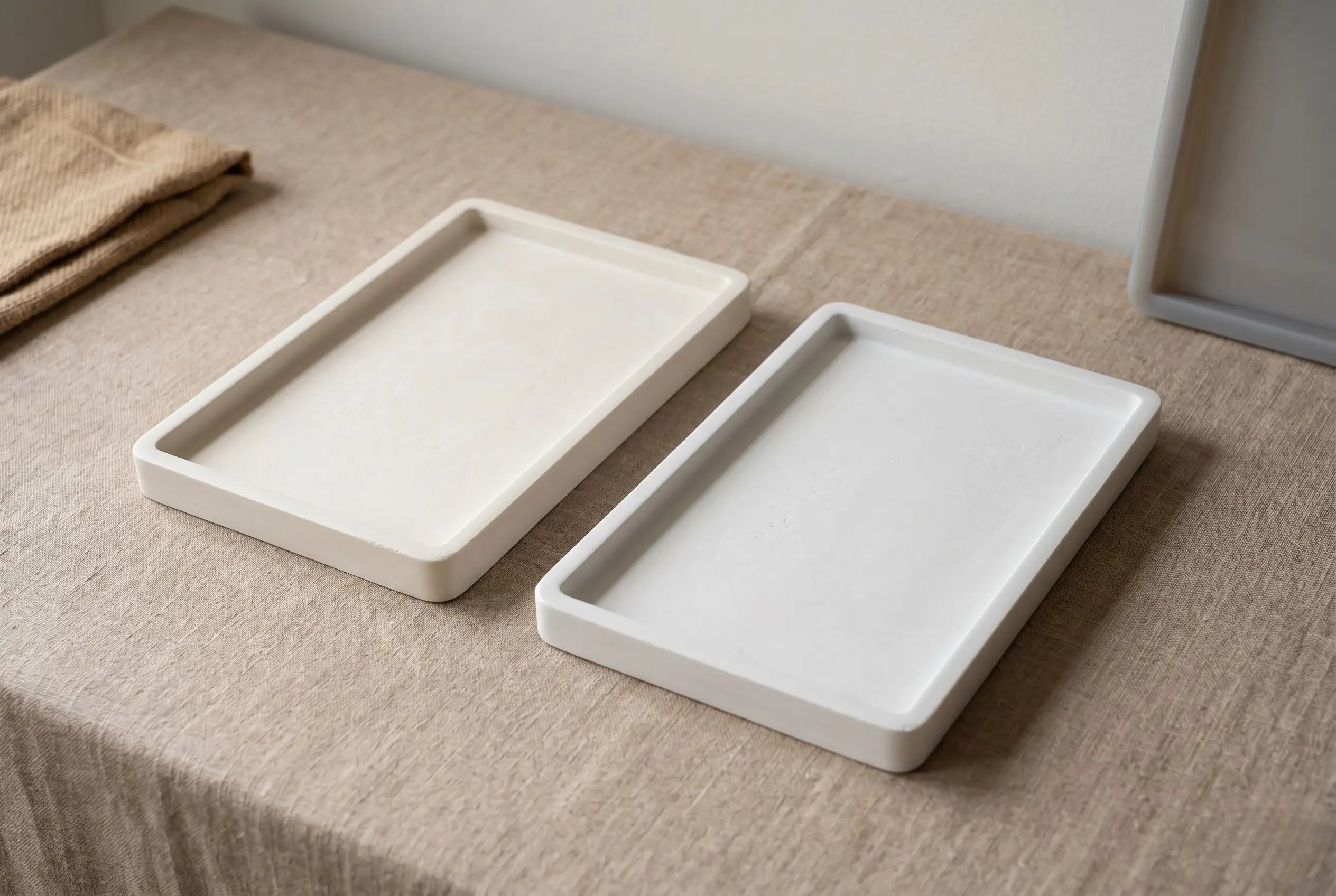 Two finished cast trays side-by-side showing the matte mineral finish of two Indian-made eco resins on a linen studio surface