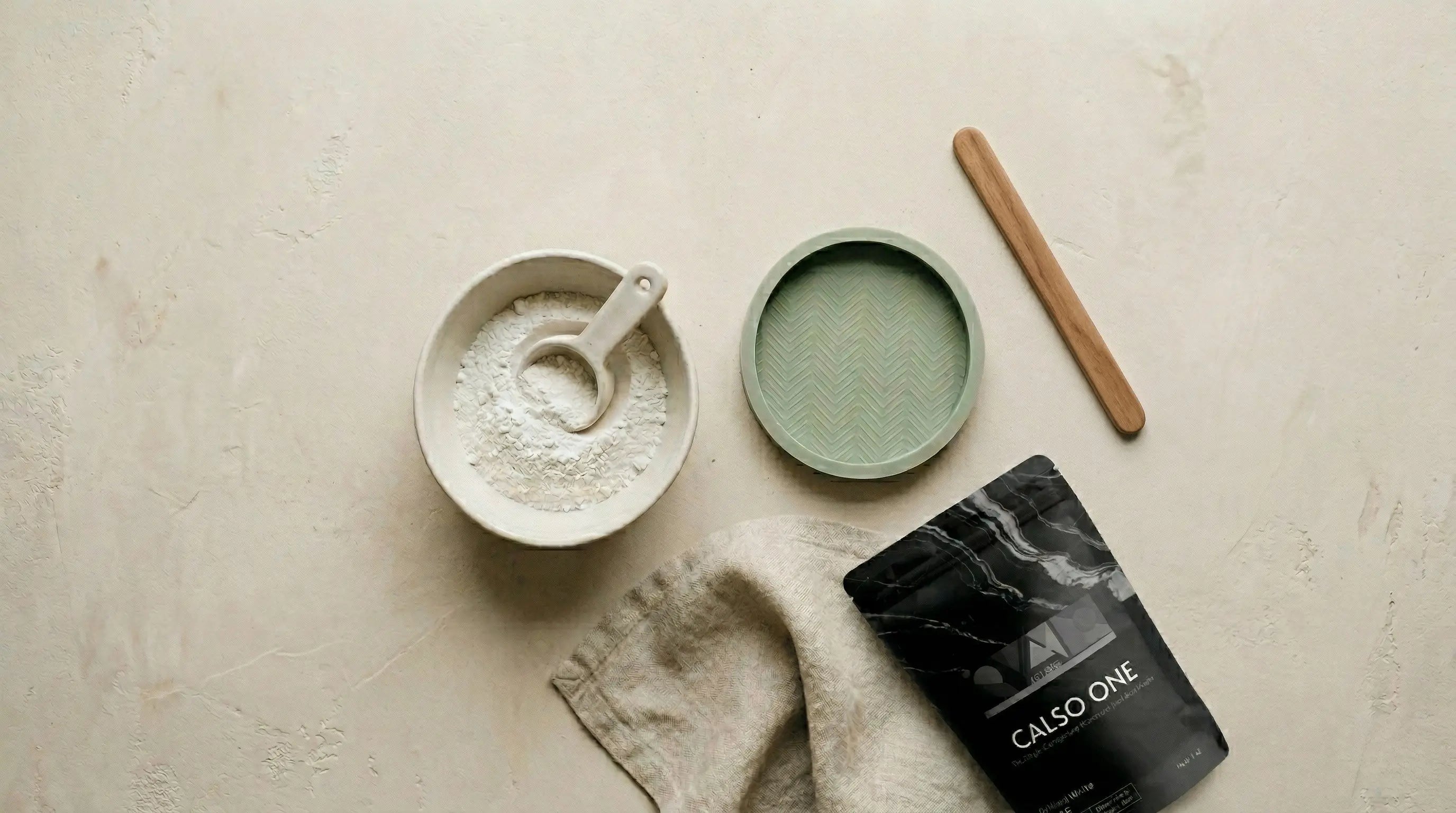 Hands mixing CALSO ONE eco resin powder with water in a silicone cup at a studio workbench in India
