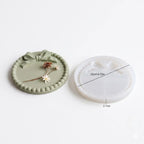 Green ceramic coaster with decorative elements and white silicone mold on a light gray background