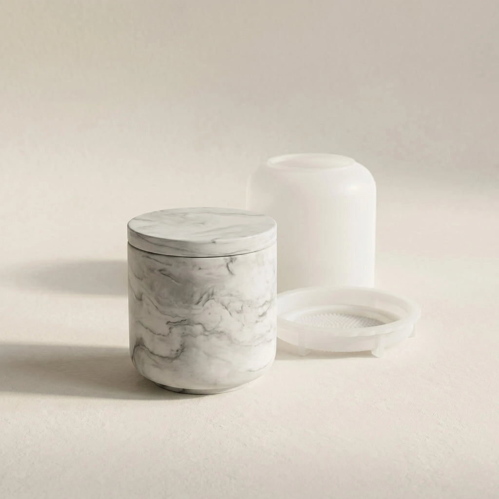 Minimalist grey marble cylindrical jar cast in eco-resin next to its translucent silicone mould set on a cream studio background.