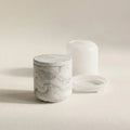 Minimalist grey marble cylindrical jar cast in eco-resin next to its translucent silicone mould set on a cream studio background.
