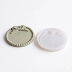 Two round silicone molds with decorative edges on a white background